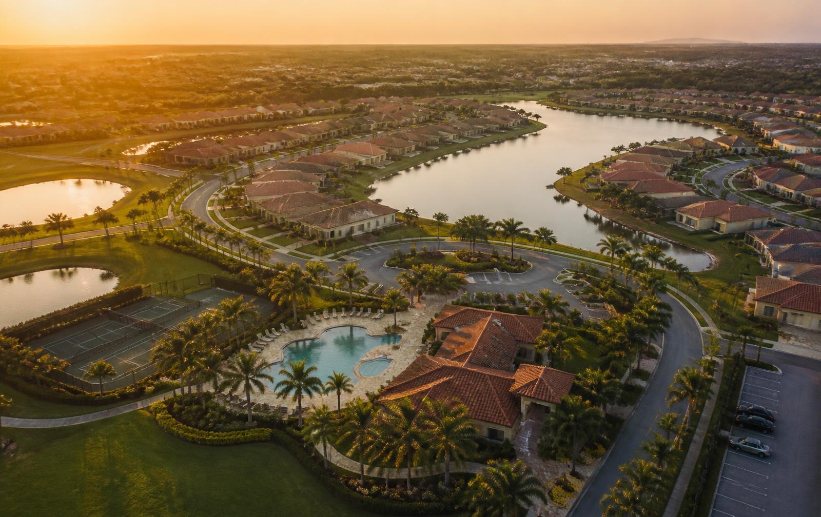 Aerial view at golden hour of a Wesley Chapel-area master-planned community with lakes, palm-lined streets and an amenity center with a pool