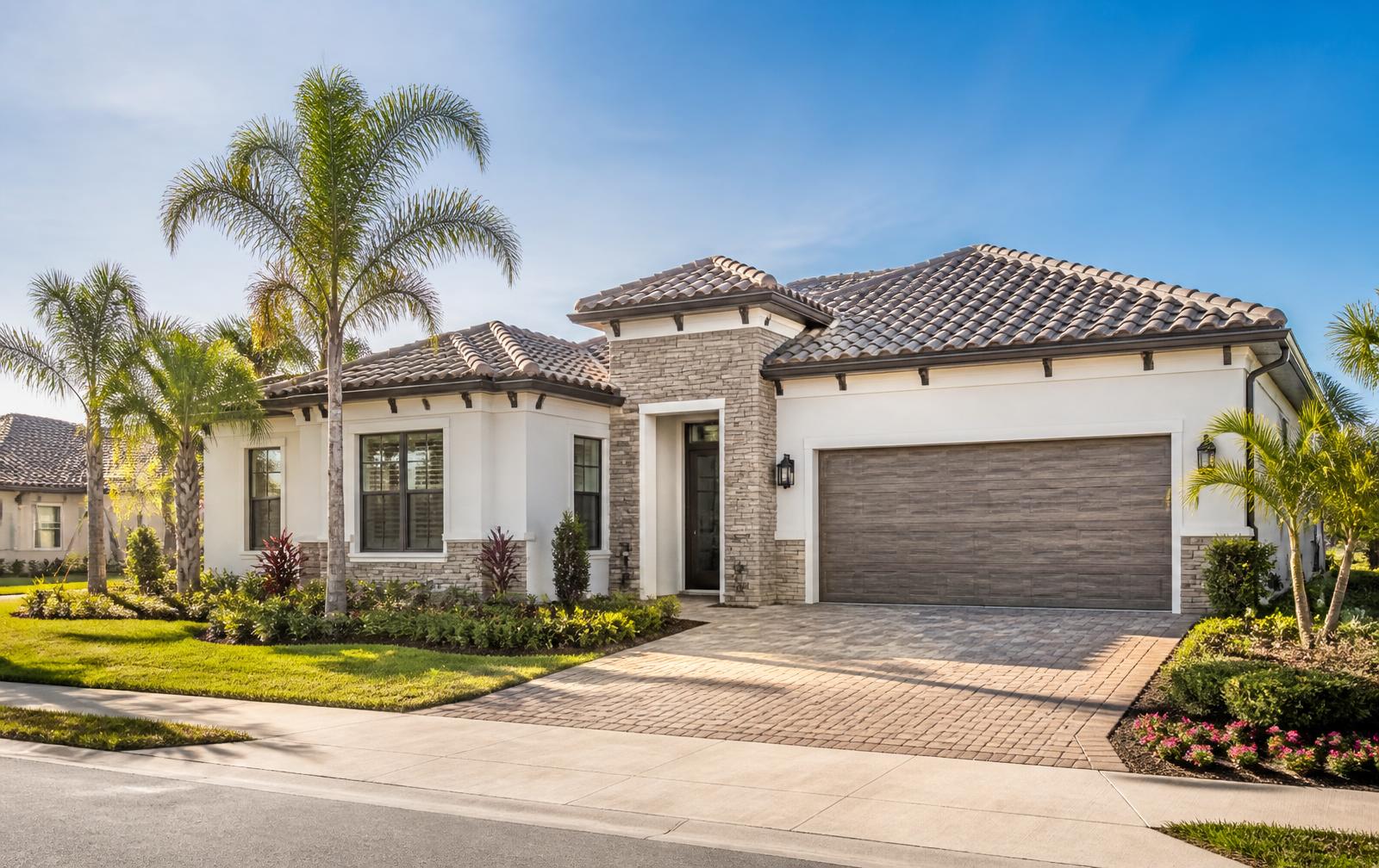A newly built Florida home with a tile roof, paver driveway and young palms in bright morning light in a Wesley Chapel–style community